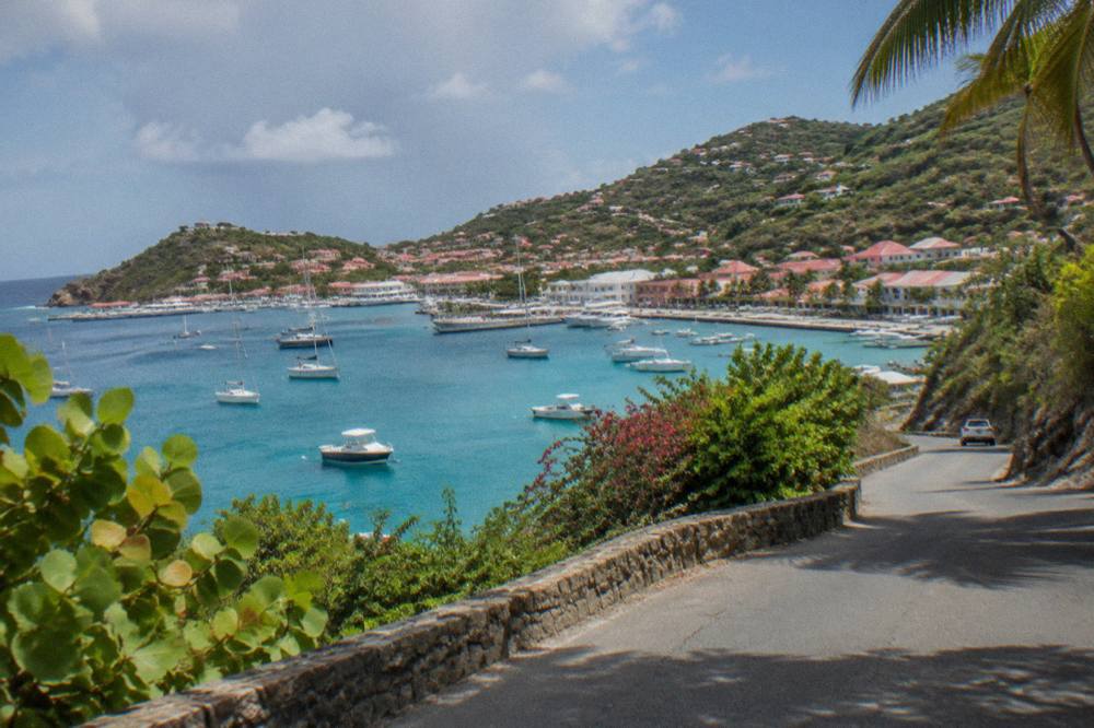 Narrow winding road climbing a green hillside above the sea