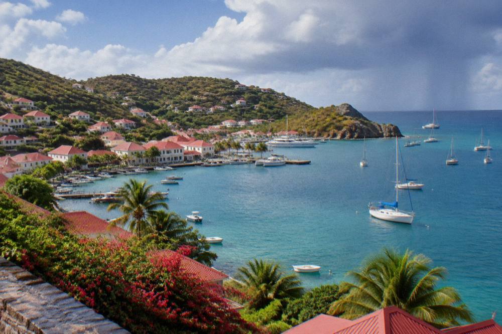 A sailboat anchored in turquoise water near a headland on St Barts