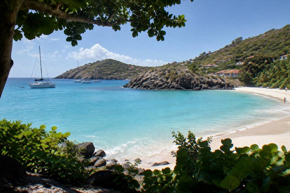 Two sandy bays separated by a rocky headland under a clear sky