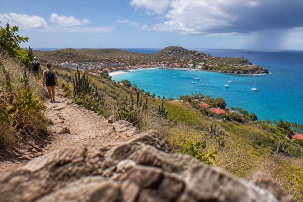 Dry coastal footpath through scrub above a blue cove