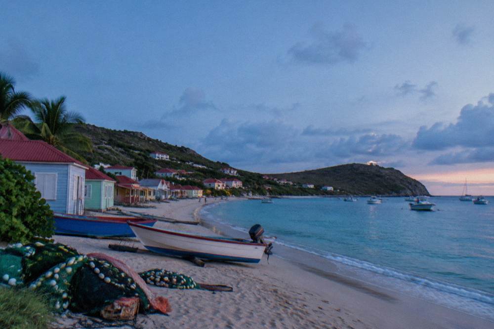 Pastel-colored houses on a hillside lane overlooking a Caribbean bay
