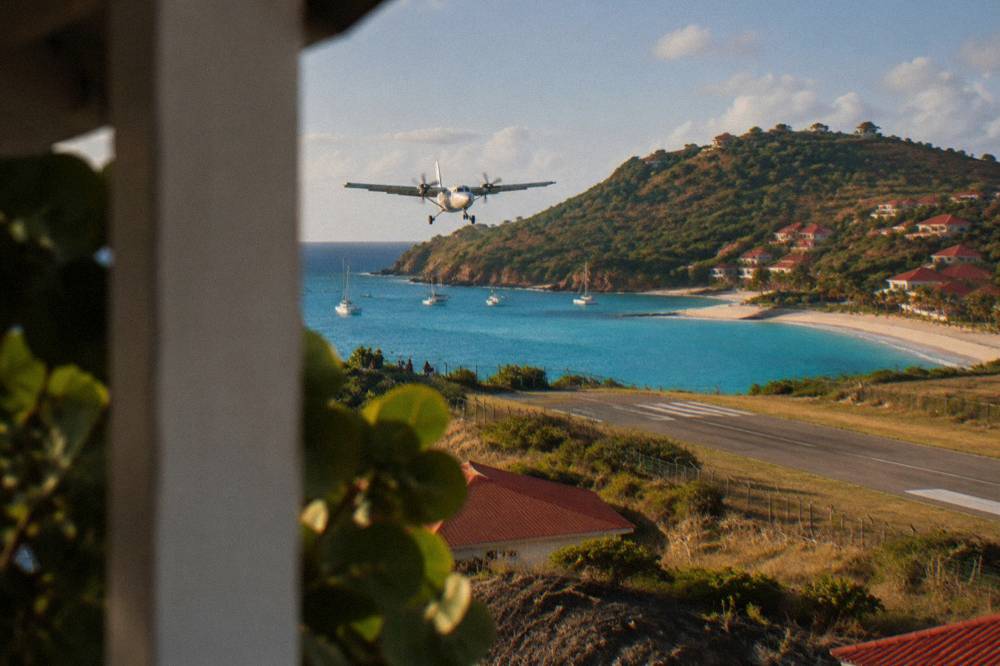 A small turboprop aircraft on a short runway beside a beach and hills