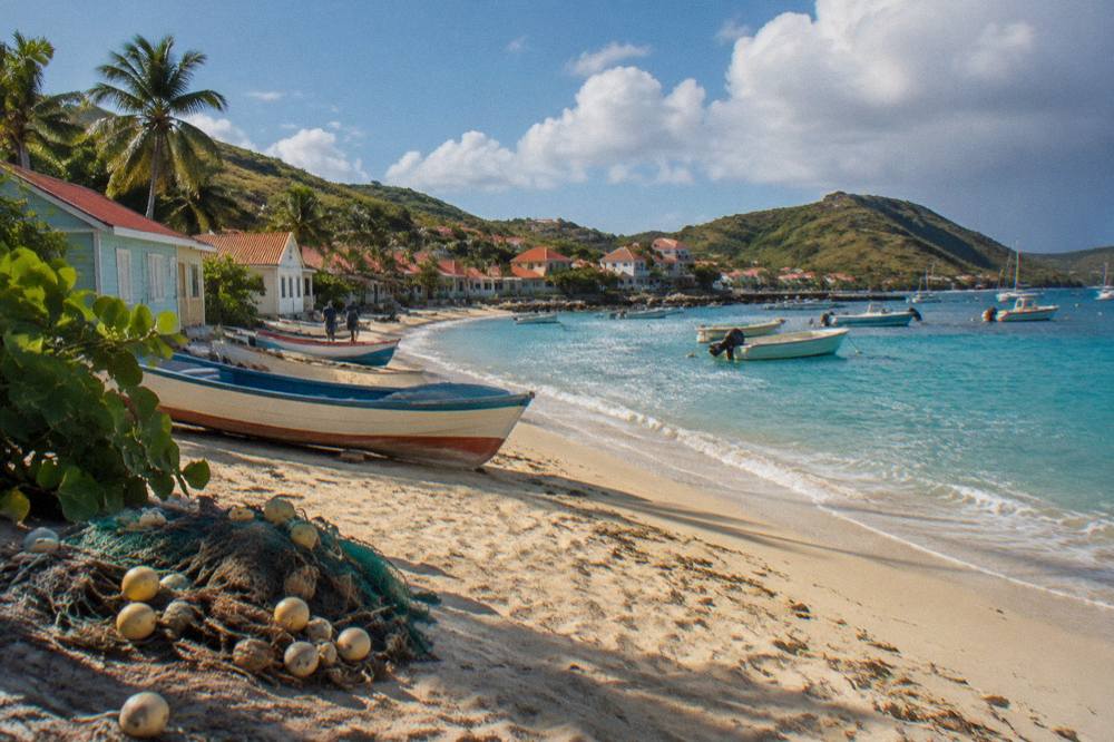 A quiet Caribbean beach with a few small wooden fishing boats near the shore