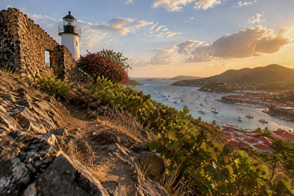 Warm evening light over a Caribbean harbour with boats at anchor and hills beyond