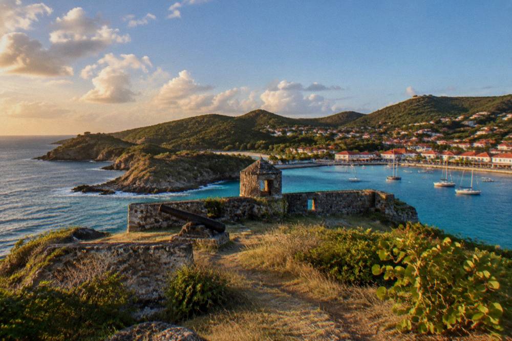Colorful waterfront street with boutiques and cafes rising from a Caribbean harbor quay