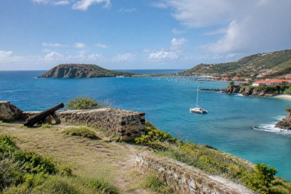 Sailing catamaran moored near a rocky green island in clear Caribbean water