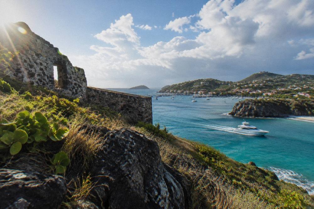 Private motor yacht cruising along a green coastline toward a Caribbean harbor