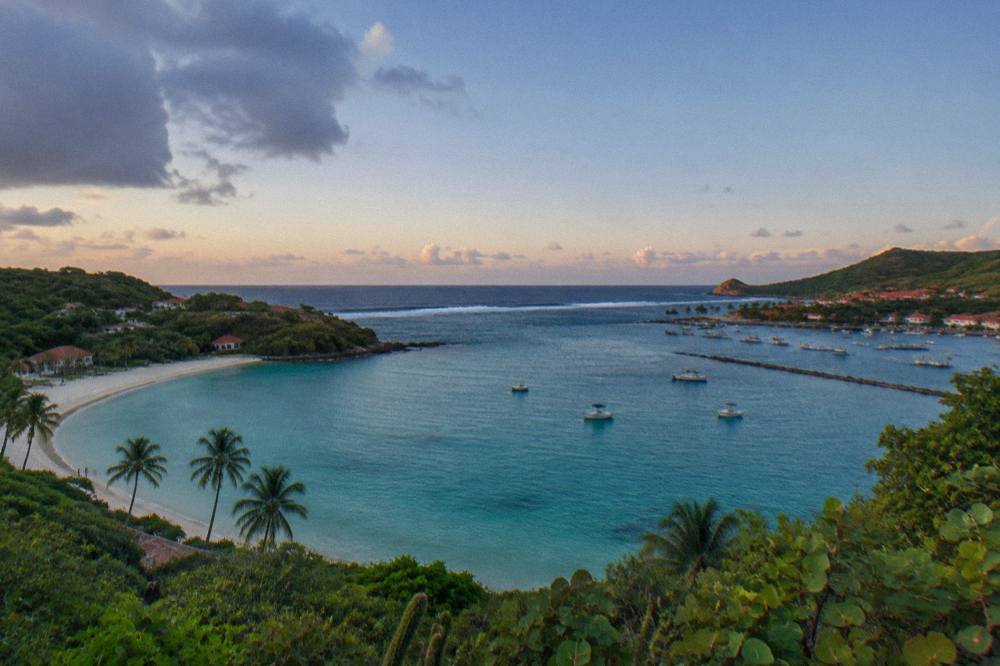 Two curved beaches side by side seen from a green headland, one with a wide lagoon and one smaller