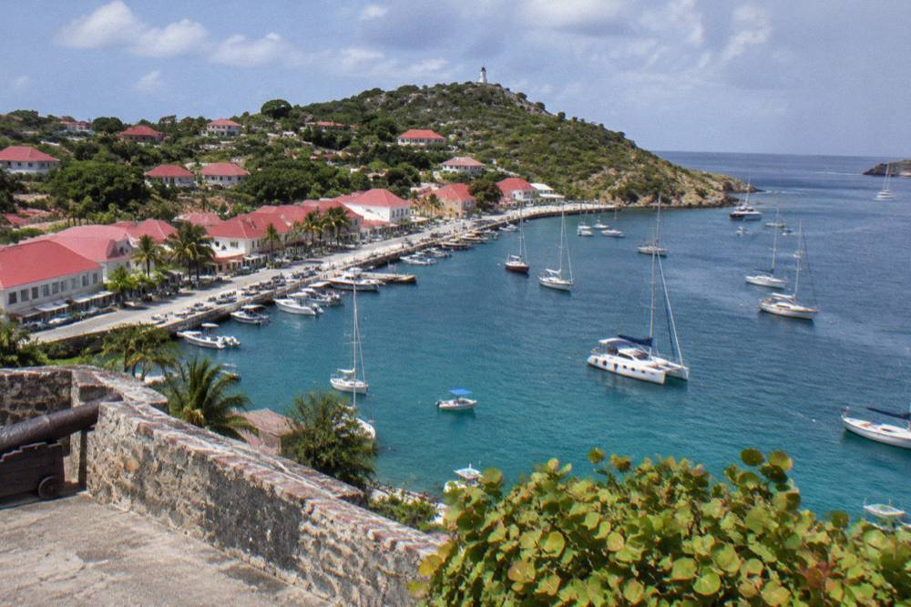 Stone fortification walls overlooking a harbour with anchored sailing boats below