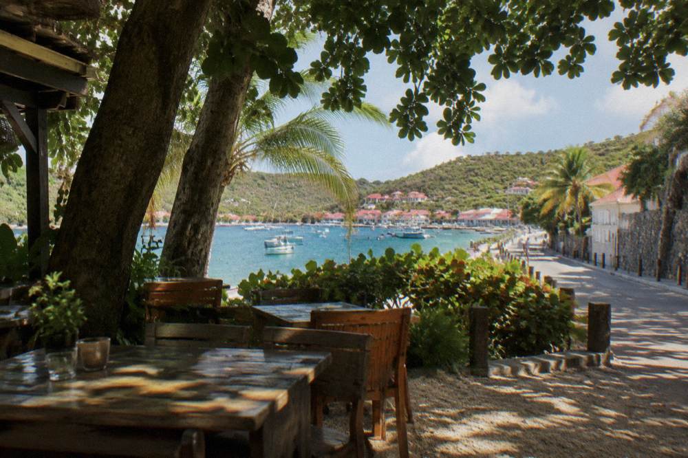 A narrow Caribbean street lined with boutiques and stone walls in a harbor town