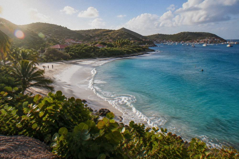 A Caribbean hillside road with tropical vegetation overlooking a bay