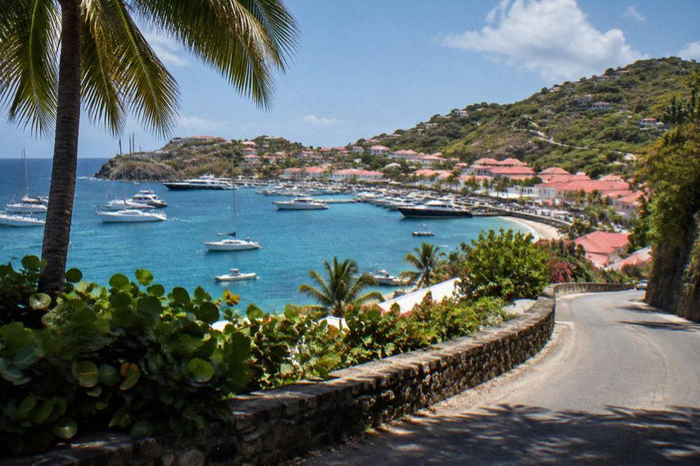 A narrow winding road climbing a green hillside on the coast of St Barts