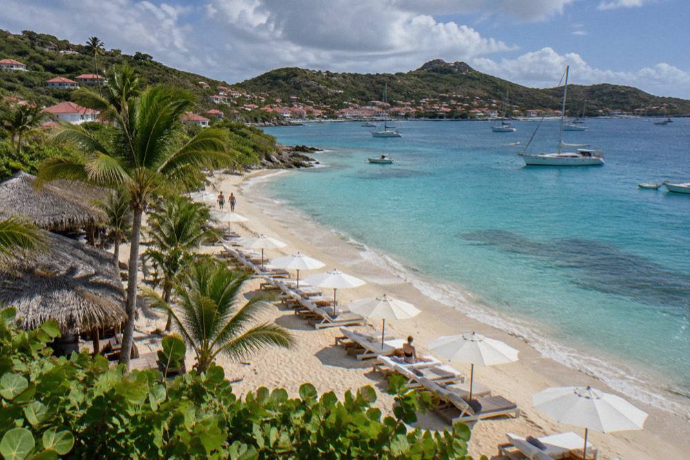 A bay on a small Caribbean island with anchored sailboats and green hills behind