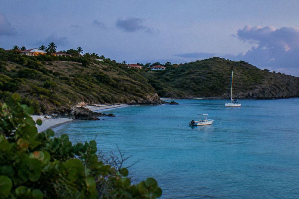 Turquoise shallow water in a small Caribbean bay with a green headland beyond