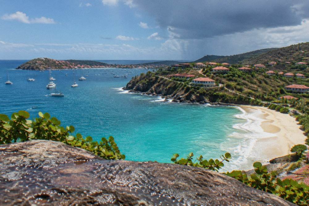 Turquoise water and a crescent of sand seen from a high vantage point on an island coast