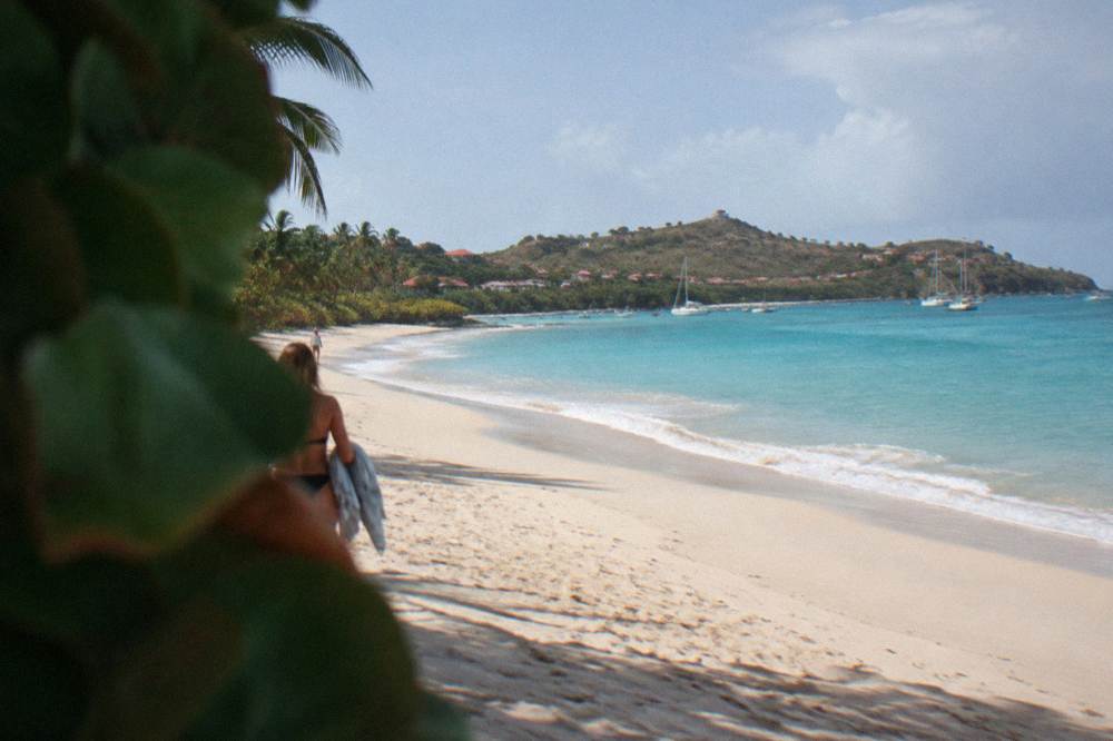 Long open beach of pale sand with dune grass and turquoise water