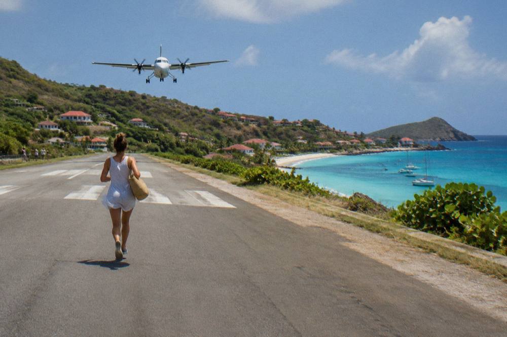 A twin-engine turboprop aircraft parked on a short Caribbean runway beside turquoise water