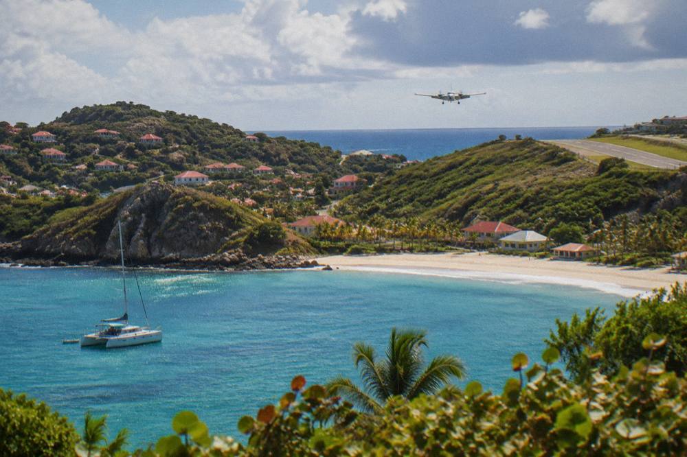 A sailing catamaran anchored in a quiet green bay in the Caribbean