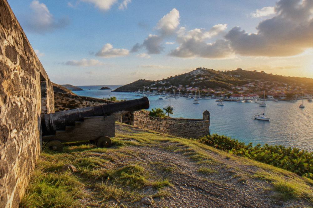 Red-roofed houses on a hillside above a Caribbean harbor with sailboats
