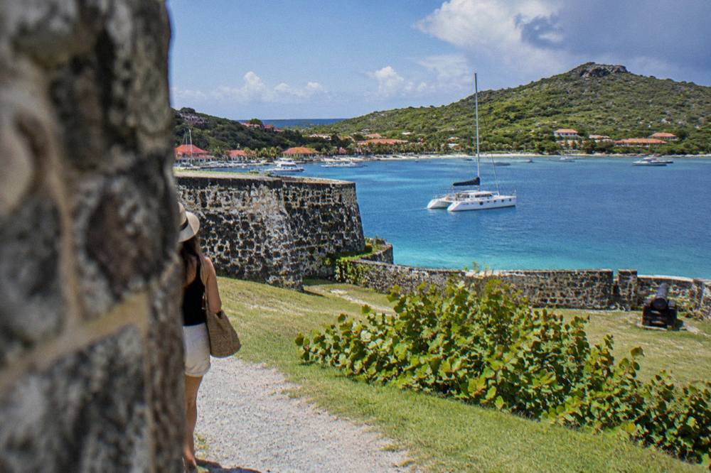 A sailing catamaran anchored in a quiet bay with green hills behind
