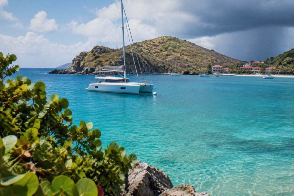 A sailing catamaran moored in a green bay at midday