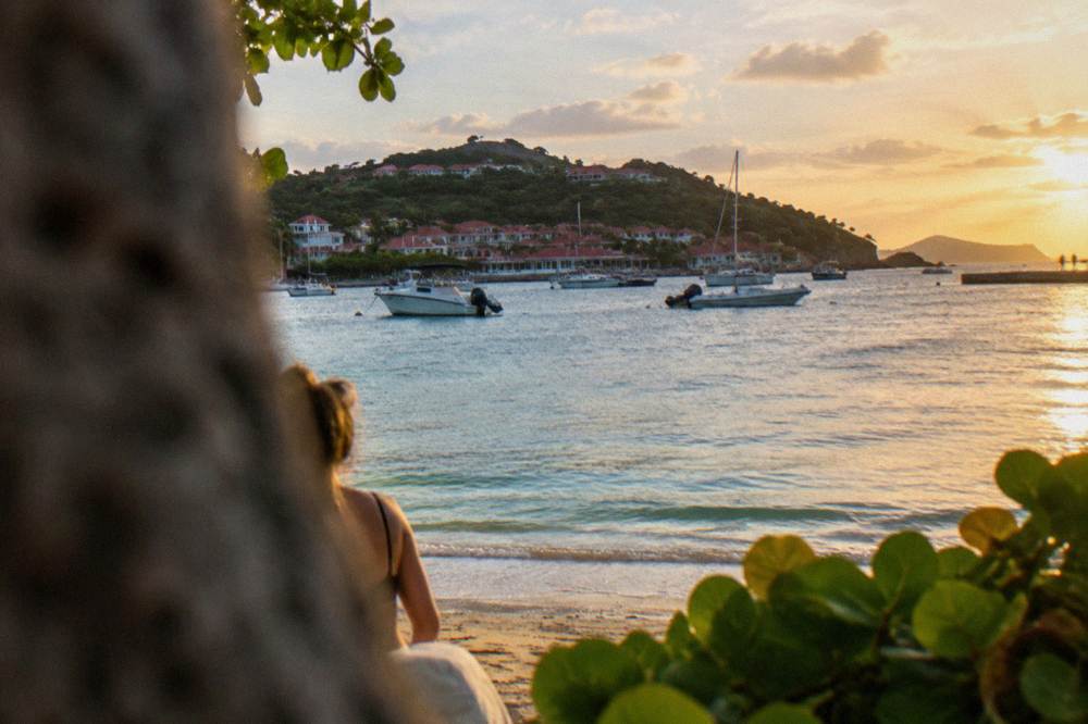Sun setting over calm Caribbean water with a headland silhouette