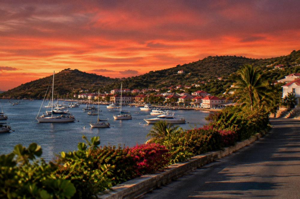 A quiet coastal road and hillside on St Barts under a deep red sky just after sunset