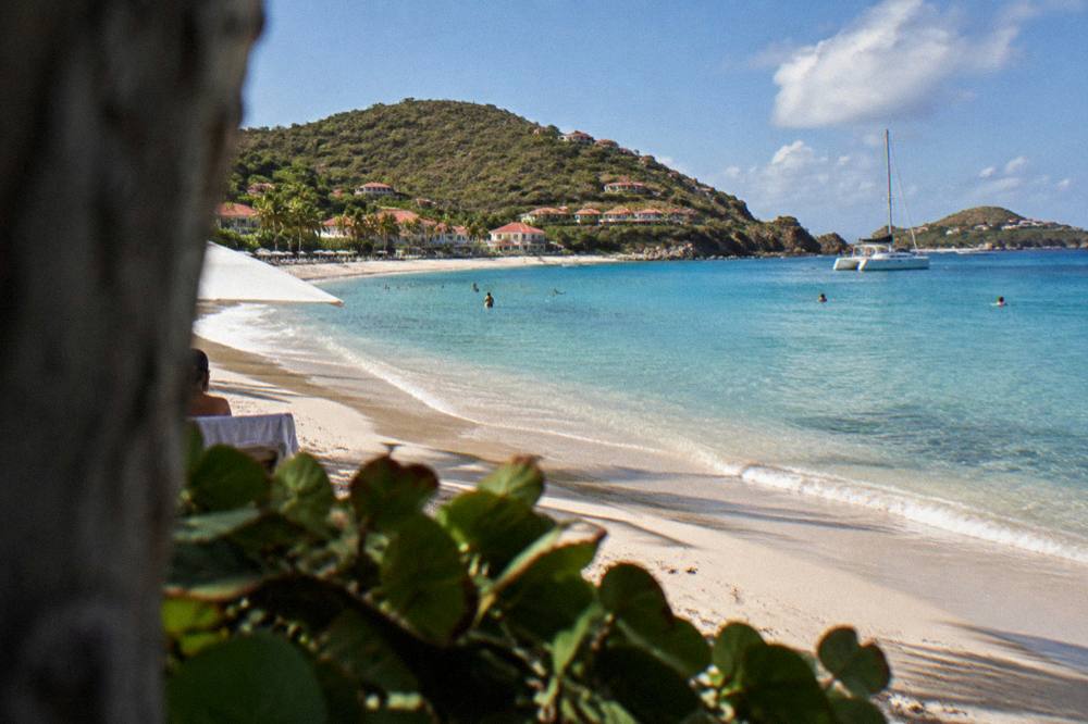 A sailing catamaran anchored in a clear bay near rocky headlands
