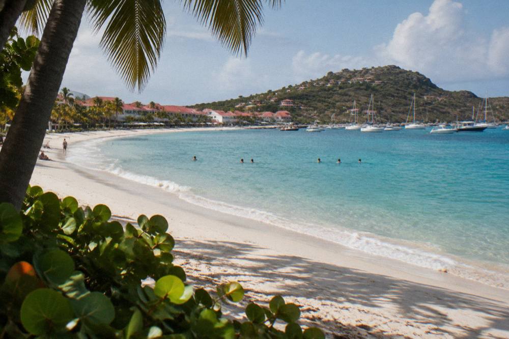 Sunlight over a calm Caribbean bay with gentle waves on a sandy shore