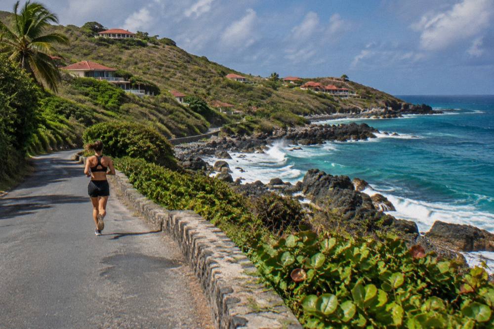 A narrow island road curving along a green hillside above the sea