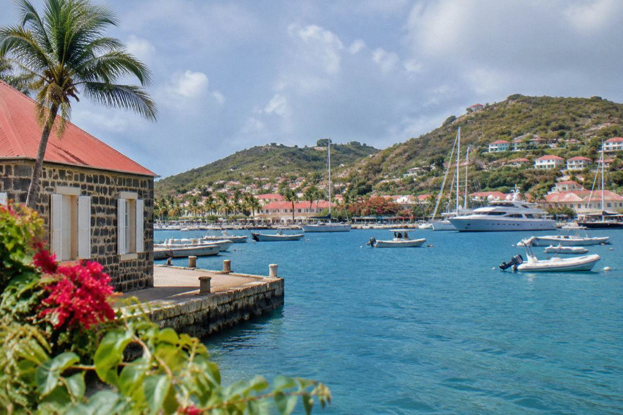 A stone building with a red roof beside the yacht harbor in Gustavia, St Barts