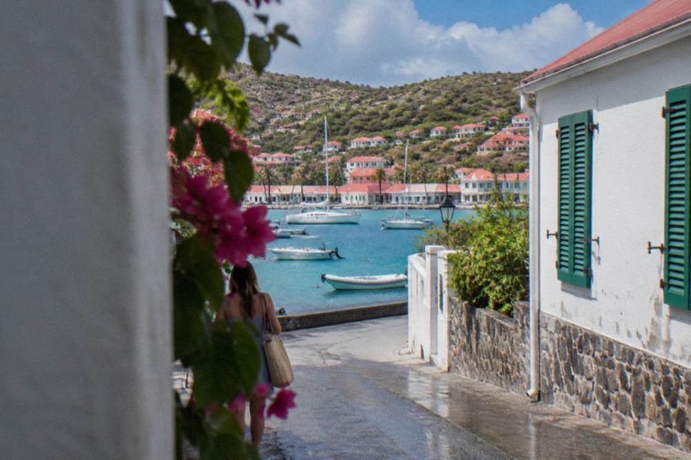 A narrow street in Gustavia with white walls, green shutters and a stone foundation