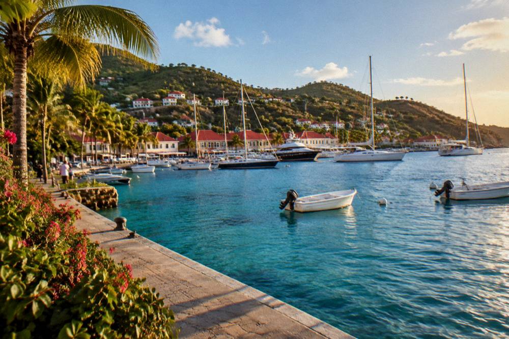 The waterfront of Gustavia at golden hour with masts and red rooftops