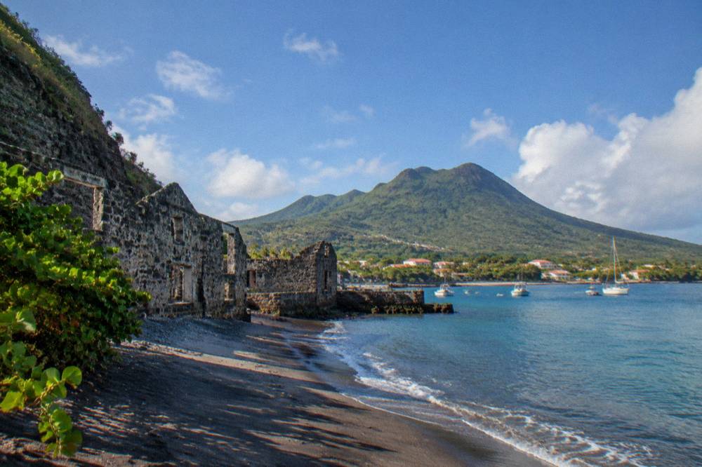 A quiet Caribbean waterfront with old stone ruins and calm blue anchorage water