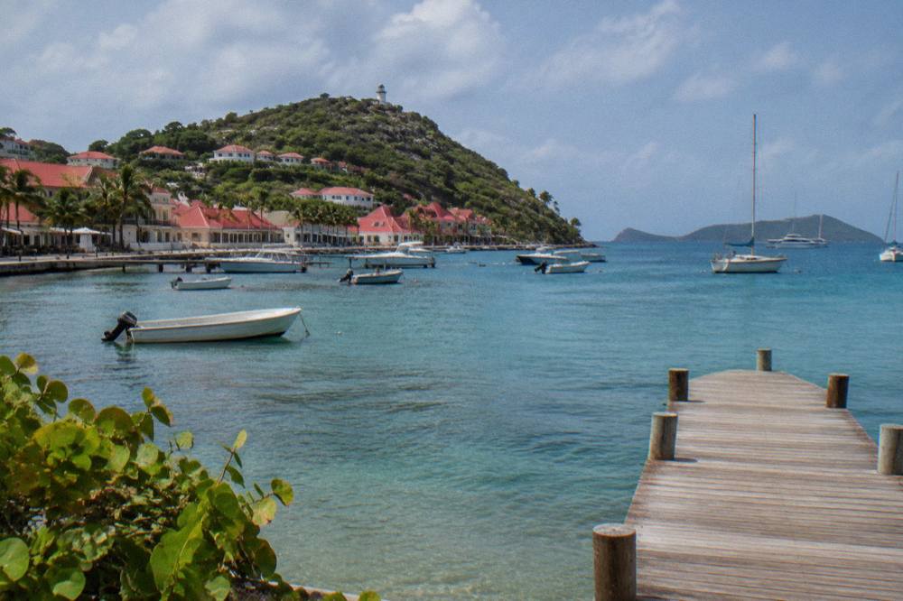 A wooden pier extending into calm shallow water toward distant islands