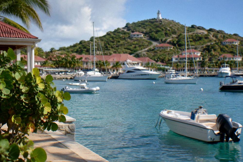 A hillside road winding above a harbor with white boats at anchor