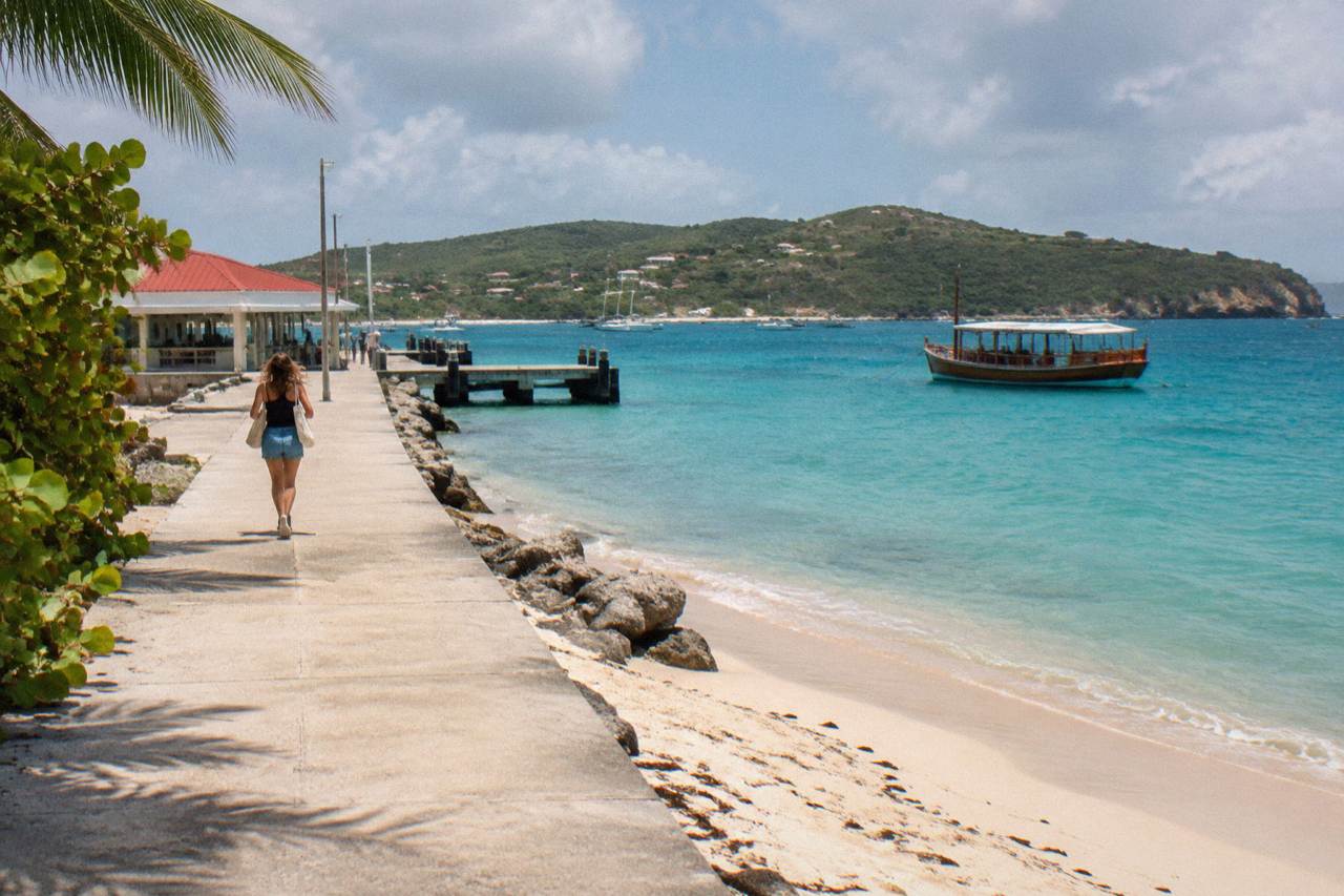 A wooden day-trip boat anchored in turquoise Caribbean water near a green island headland