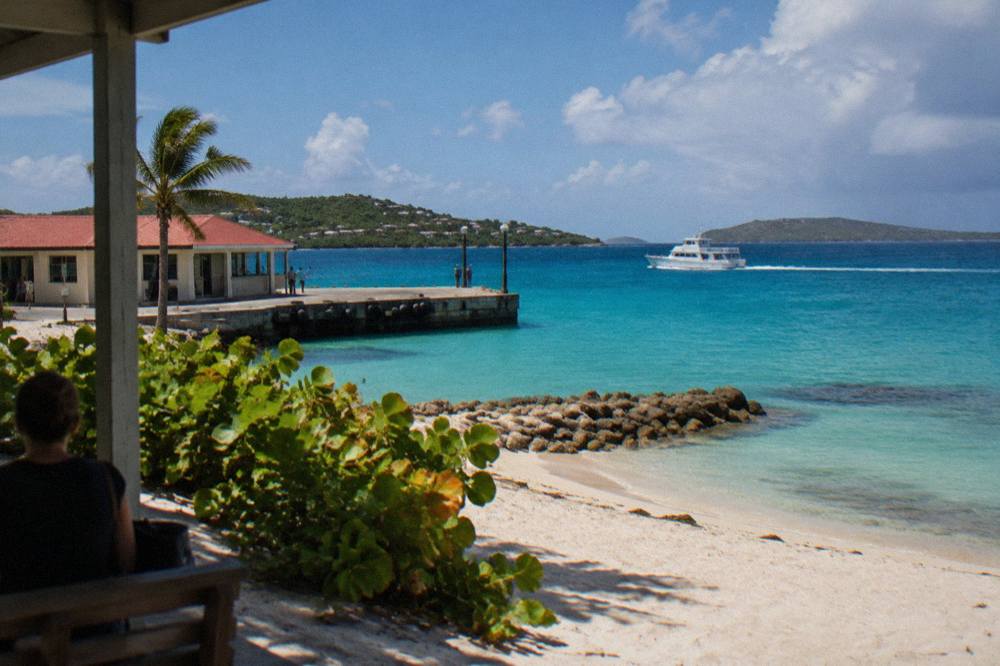 A small white ferry cutting across open blue water between green Caribbean islands