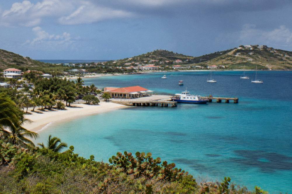 An aerial view of two green Caribbean islands separated by a band of deep blue water