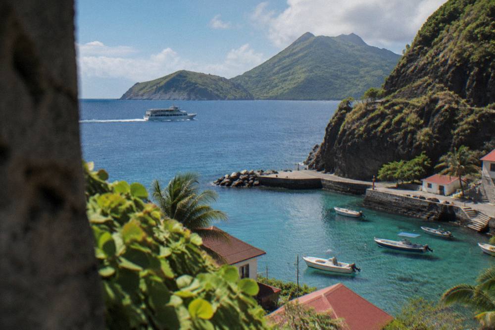 A ferry boat cutting across open blue water between green islands