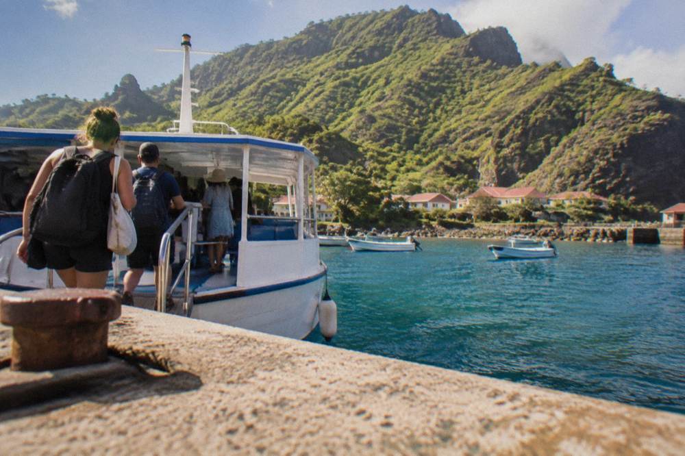Passengers boarding a small passenger ferry at a Caribbean dock in morning light