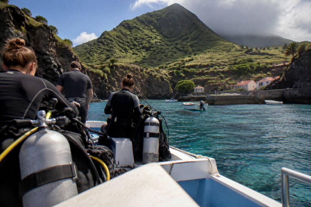 Divers preparing gear on a small boat above clear reef water