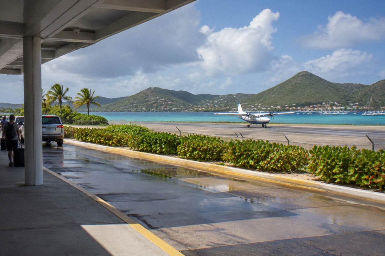 A small turboprop aircraft on a short Caribbean runway with green hills behind it