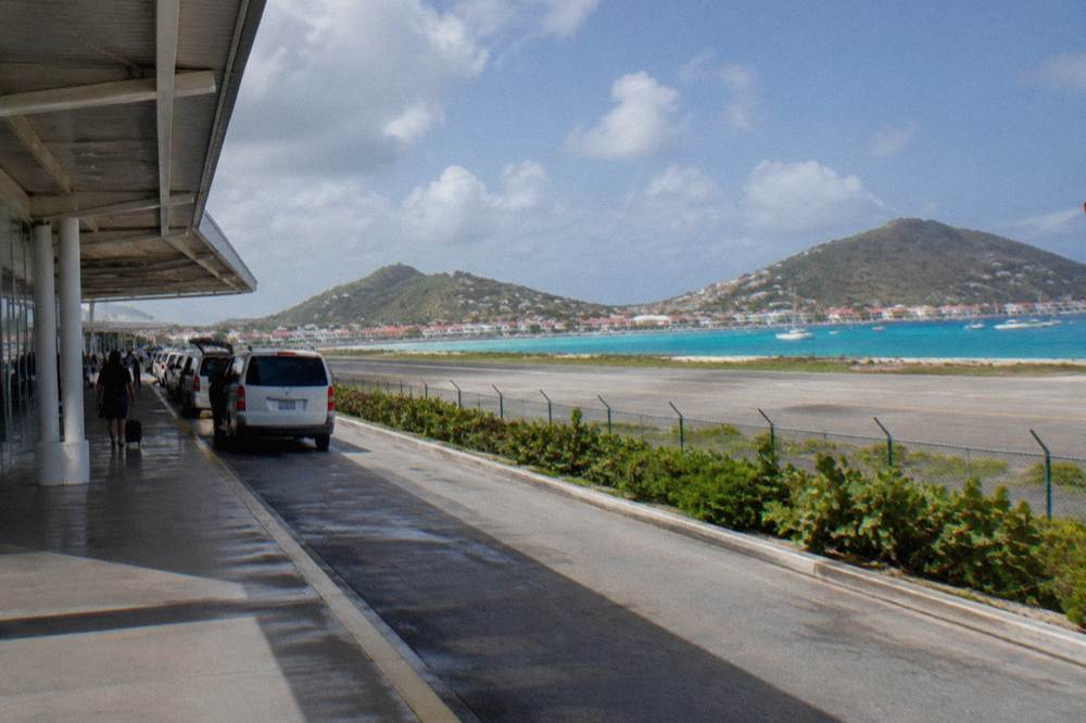 Harbour buildings with red roofs along a Caribbean waterfront under scattered clouds