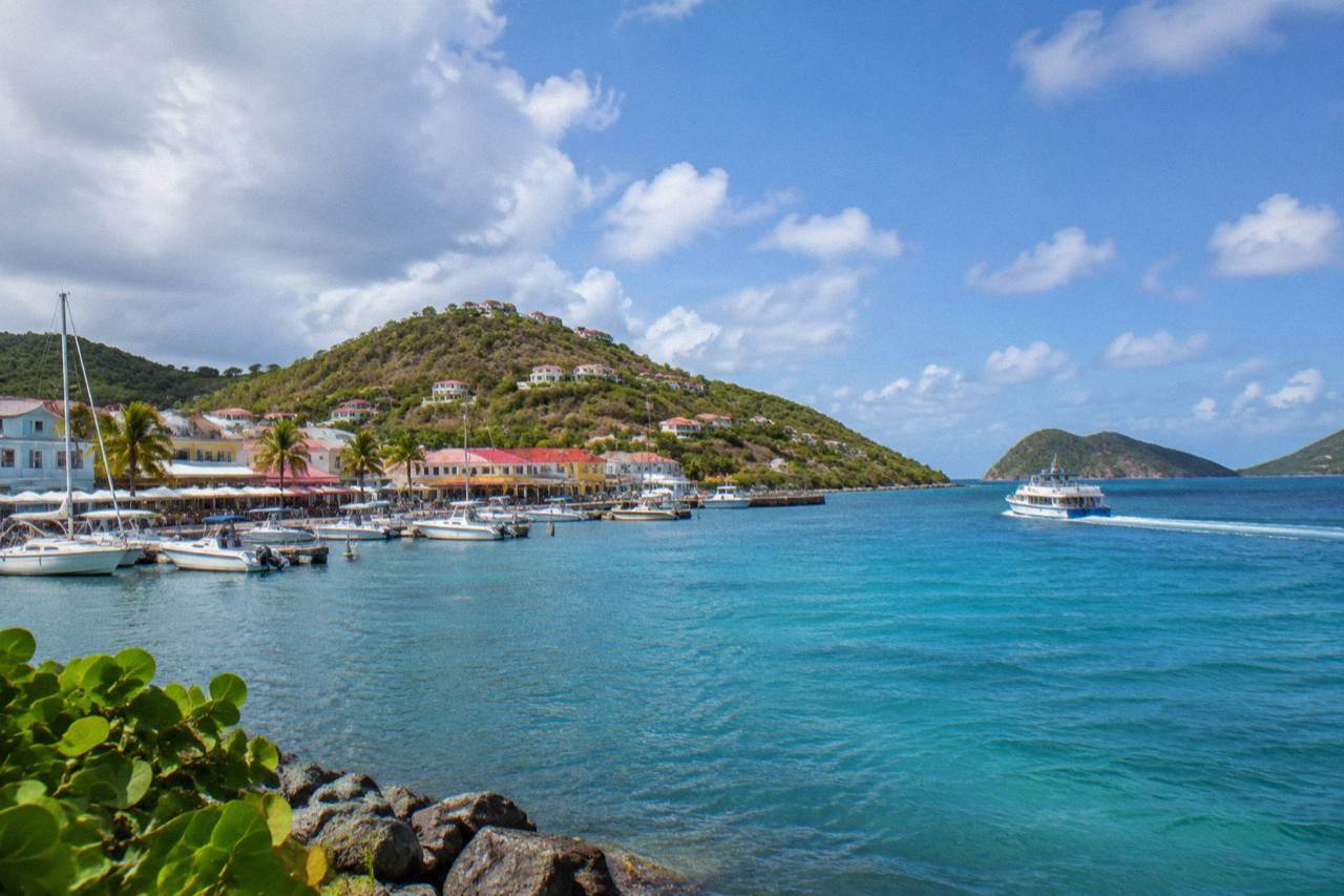 A ferry boat crossing open blue Caribbean water between green islands under a bright sky