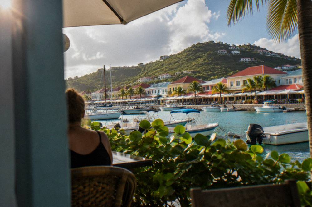 Colourful waterfront shops along a Caribbean main street with mountains behind