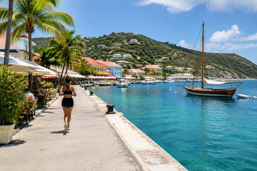 Wooden sailboat anchored in a quiet bay with clear water and green hills