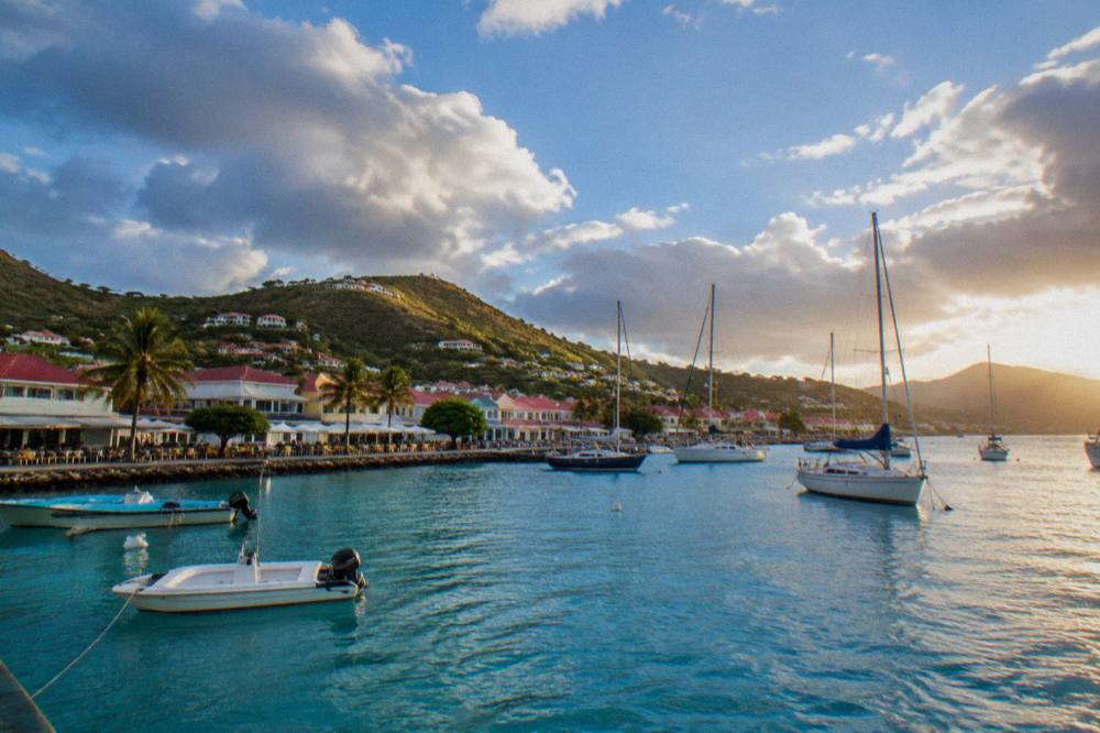 Sailing yachts moored in a harbour at sunset with hills silhouetted behind
