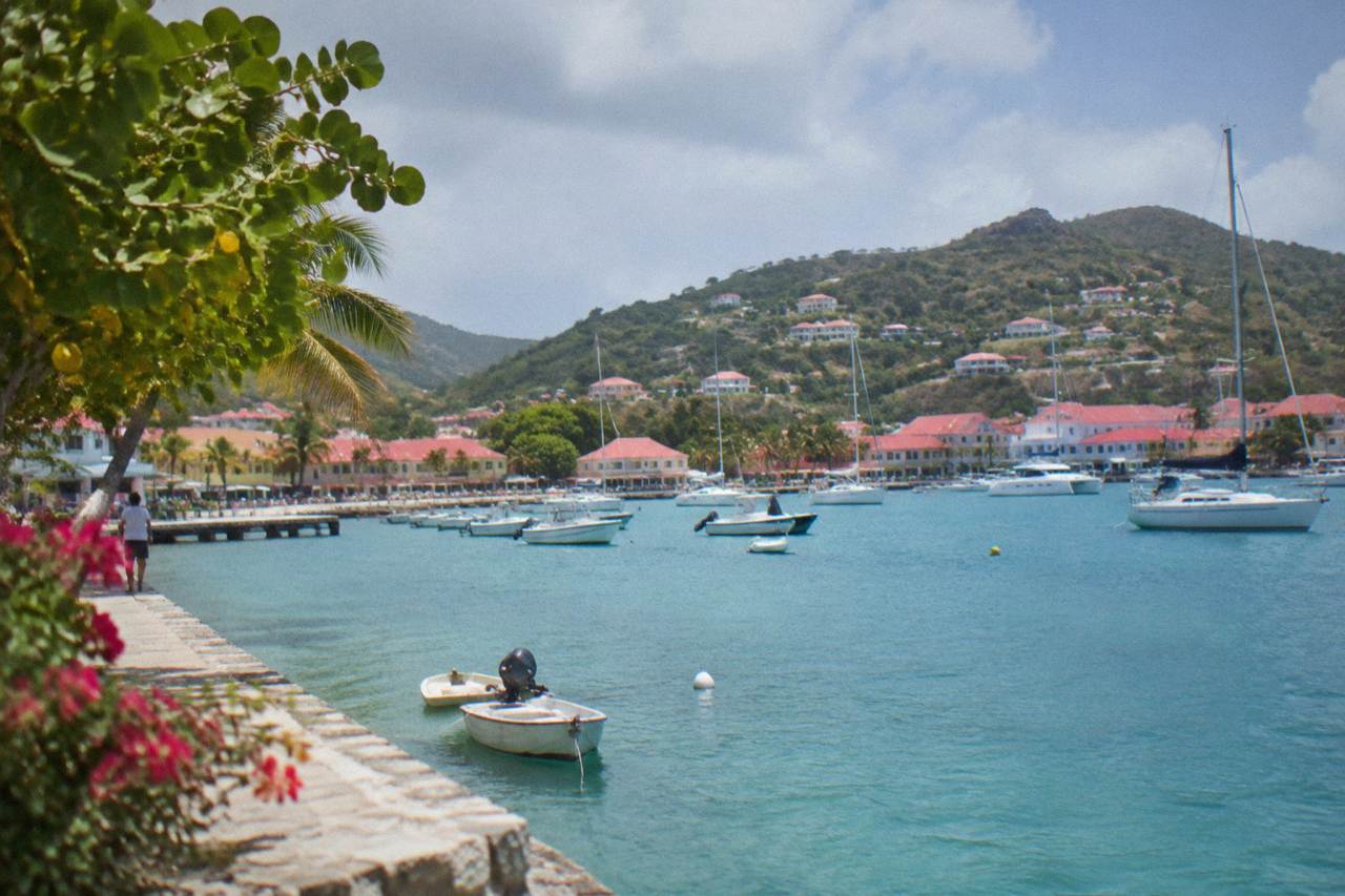 A small Caribbean harbour town with red roofs and hills rising behind moored sailboats