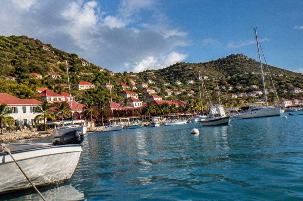 White buildings with red roofs around a harbour filled with yachts at golden hour